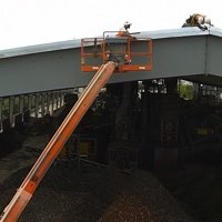 Men in basket at peak of 200 clear over scrap processing facility.